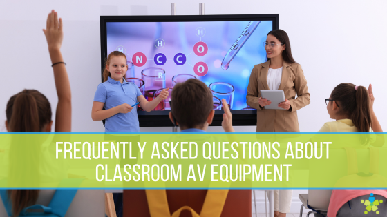 An elemntary school girl and teacher standing in front of a display at the front of the class as students raise their hands to ask questions.